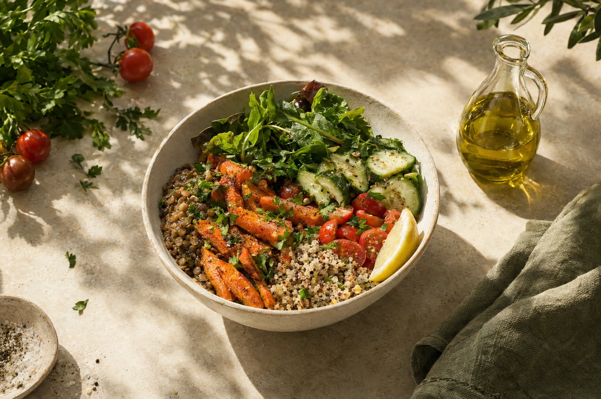 Bunte Schale mit Linsen, Quinoa, Gemüse, frischen Kräutern und Zitrone im Sonnenlicht